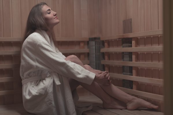 seitenansicht der jungen frau sitzend auf holzbank in der sauna